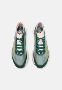 Zielone i różowe buty sportowe z siateczkową cholewką, sznurowanym zamknięciem i wzorzystą wkładką. Posiadają złote akcenty oraz lekką podeszwę.