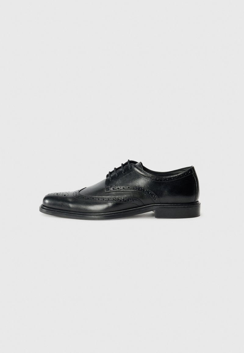 Chaussure habillée en cuir noir avec des détails en brogue, une finition lisse, un système de laçage et un petit talon. Design classique et formel.