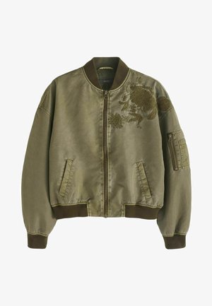 Maslinasto zelena bomber jakna od glatkog materijala s cvjetnim vezom, zatvaranjem na zip, rebrastim manžetama i dva bočna džepa s dodatnim džepom na ruci sa zipom.