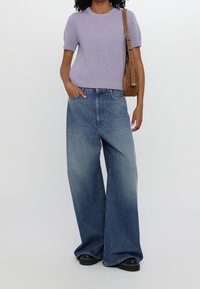 Top a coste lilla chiaro con maniche corte, abbinato a jeans larghi in denim blu sbiadito e scarpe con suola spessa nera.