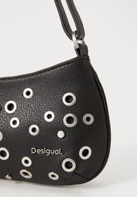 Borsa a spalla in pelle nera con decorazioni in occhioletto argentato, texture imbottita e dettagli del logo. Include una sottile tracolla regolabile.