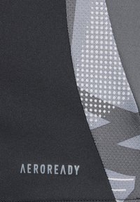 Zwart en grijs stof met een gladde textuur, voorzien van een geometrisch patroon en kleine stippen. Toont de tekst "AEROREADY" in lichtgrijs.