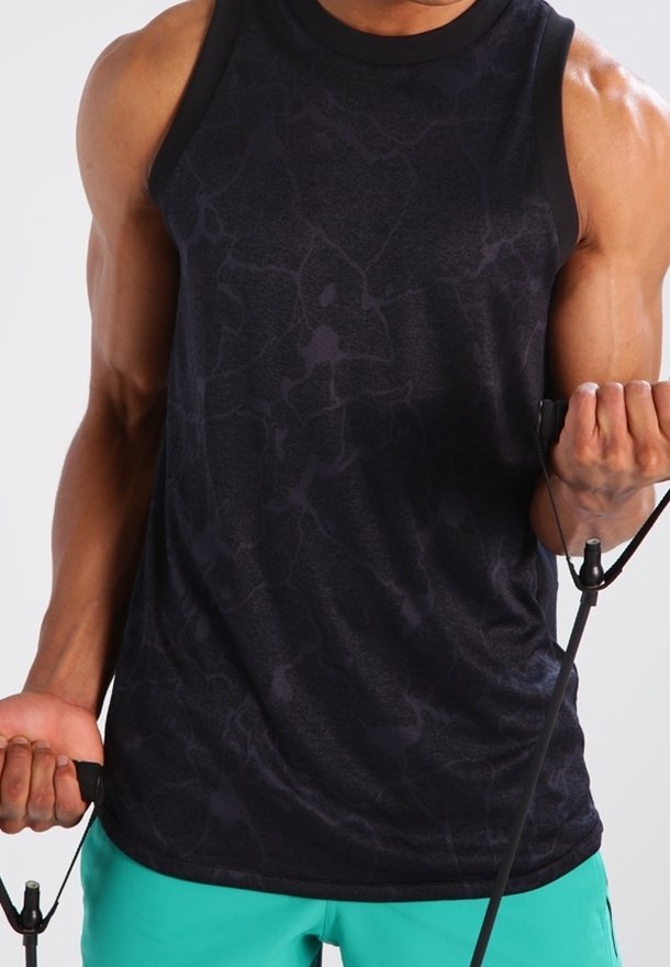 Svart ärmlös träningslinne med ett strukturerat mönster, kombinerat med teal träningsshorts, och håller i motståndsband.