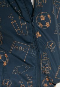 Navy blue vest featuring orange line drawings of sports, science, and toys, with a zip closure and a soft, smooth texture.