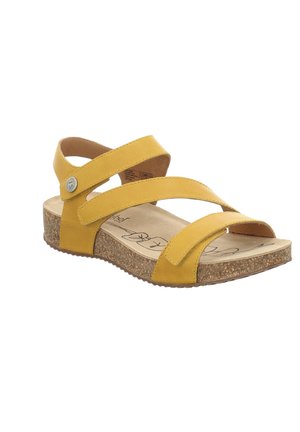 Sandales en cuir jaune avec des sangles croisées, semelle en liège et semelle en caoutchouc texturé. Présente un accent en forme de bouton sur la sangle.