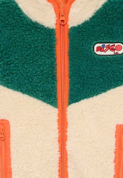Grüne und cremefarbene Fleecejacke mit orangefarbener Reißverschluss und Taschen, mit einem "Disco"-Aufnäher im oberen rechten Brustbereich.