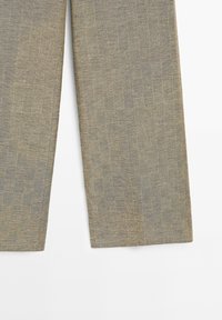 Pantalon en lin beige coupe droite, visible de la mi-cuisse jusqu'à l'ourlet sur fond blanc.