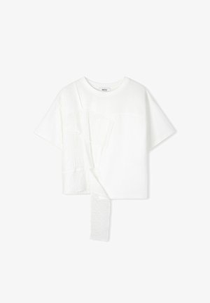 Bílý tričko s krátkým rukávem a asymetrickými látkovými panely, s texturovaným volánkem na levé straně. Kulatý výstřih, pohodlný střih.
