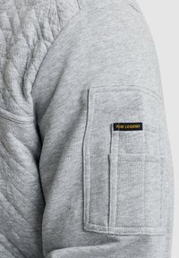 Grijze sweatshirt met geborduurde schouderdetails, voorzien van een patch pocket op de mouw en een "PME LEGEND" label in zwart en geel.