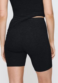 Svarta tajta shorts i stretchigt material, med en sl�ät yta och midjan-längd som når till mitten av låret, samt en hög midjebandsdesign.