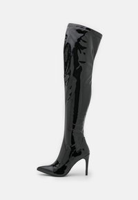 Botas de cuero patentado negras hasta el muslo con puntera afilada y tacón de aguja. Acabado suave y brillante. Costuras reforzadas en la parte superior.