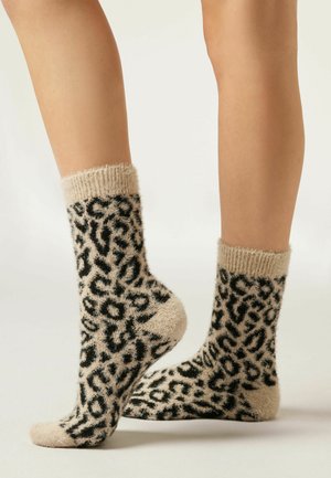 Chaussettes à imprimé léopard en beige et noir, fabriquées en matériau doux et texturé. Comprend un large bord côtelé et un corps moelleux.