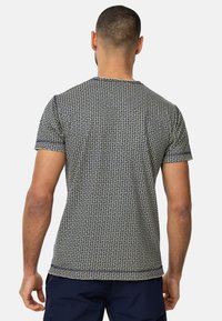 T-skjorte med korte ermer i marineblå med et geometrisk mønster. Laget av lett stoff, med rund hals og en tettsittende passform.