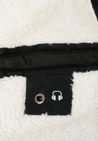 Fuzzy white fabric with a black denim strip, featuring a headphone jack with a copper grommet and white headphone graphic.