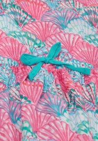 Blommönstrad tyg med rosa och aqua snäckor, med en texturerad yta och en turkos båge högst upp som accent.