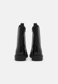 Czarne skórzane botki za kostkę o gładkim wykończeniu, z zamkiem błyskawicznym z tyłu i niskim, teksturowanym obcasem.