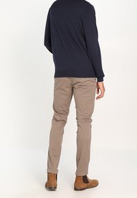 Merimekkoset, vaaleat chinot ja ruskeat nilkkurit. Merimekkosessa on pyöreä kaula-aukko; chinot ovat kapeat ja sileäpintaiset.