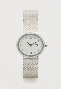 Zilveren polshorloge met een gaasarmband, een ovale wijzerplaat, kristallen uurmarkeringen, Romeinse cijfers op 12 en 6, en een klein vlaglogo op de wijzerplaat.