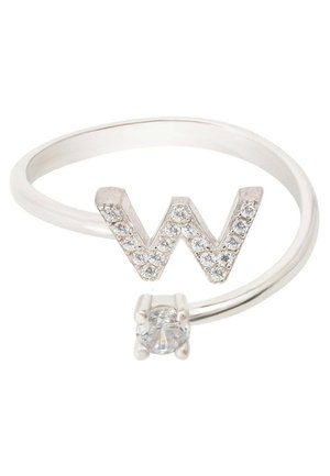 Bague ouverte en argent avec une lettre W ornée de cristaux à une extrémité et un cristal clair rond unique à l’autre extrémité.