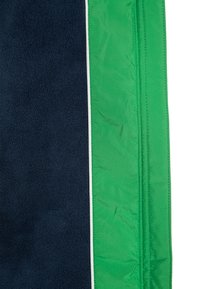 Gros plan sur un tissu en polaire bleu marine à côté d'un tissu vert vif cousu, avec une fine bande blanche entre les deux.