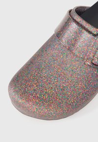 Glittery clog shoe with a rounded toe, made of iridescent material. Features colorful sparkles in various shades across the surface.