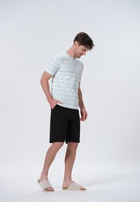 Lys grøn og hvidstribet t-shirt, sorte shorts og beige slip-on sandaler. Casual fit med korte ærmer og sidelommer.