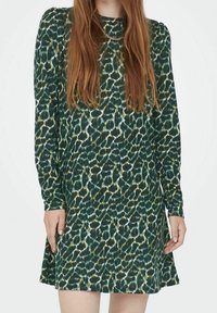 Vestido verde con estampado y mangas largas, que presenta una tela texturizada y una silueta acampanada. El patrón incluye tonos de verde y crema.
