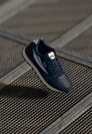 Navy blue athletic shoe with a smooth leather upper, white and purple accents, and a textured rubber sole. Features lacing system and logo.