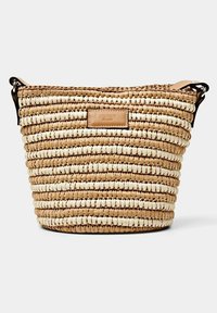 Sac à main rond tressé avec des rayures beige et blanches, bandoulière en cuir et une étiquette en cuir portant l'inscription "Esprit de Corp" à l'avant.