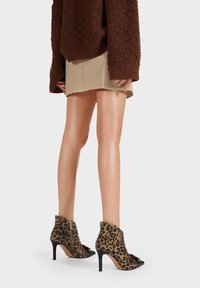 Stivaletti alla caviglia con stampa leopardata, punta nera, tacco a stiletto e chiusura con zip sul retro; texture morbida e motivo distintivo.
