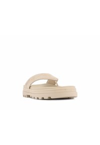 Vaaleanbeigein flip-flop, jossa on pehmeä nahkaremmi, teksturoitu pohja ja paksu kumipohja, jossa on uria pitoa varten.