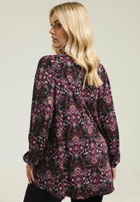 Langærmet sort bluse med et farverigt blomstermønster i nuancer af pink, lilla og hvid. Har en afslappet pasform og detaljer med gathered skulder.