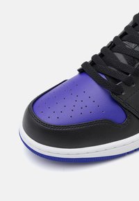 Černé kožené tenisky s fialovým špičkovým boxem, perforovaným detailem, černými tkaničkami a bílou mezipodešví s modrými akcenty na podešvi.