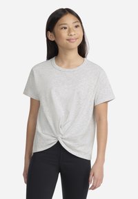 T-shirt en maille gris clair à manches courtes, avec un nœud torsadé à l'avant de la taille, associé à des leggings noirs.