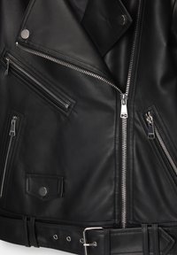 Svart läderbikerjacka med flera dragkedjor, tryckknappar, midjebälte och en asymmetrisk design med distinkta sömmar.