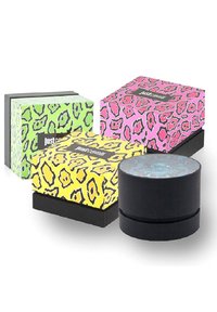 Cuatro cajas de embalaje en colores vibrantes: verde, amarillo, rosa y negro. Cada una cuenta con audaces patrones de estampado de leopardo y formas rectangulares o cilíndricas.