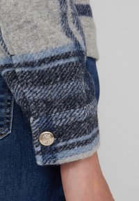 Wollen geruite shirtmanchet in grijs, blauw en marineblauw; beschikt over een zilveren knop met een gestructureerde afwerking en een detail van een leeuwenembleem.