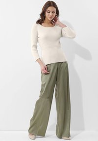 Geripptes Cremefarbene Sweater mit quadratischem Ausschnitt und Dreiviertelärmeln, kombiniert mit hoch taillierten, olivgrünen, weit geschnittenen Hosen.