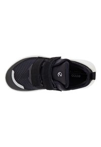 Baskets noires avec tige en mesh et accents en daim, dotées de deux bandes velcro et d'une semelle en caoutchouc blanche. Logo de la marque visible à l'intérieur.