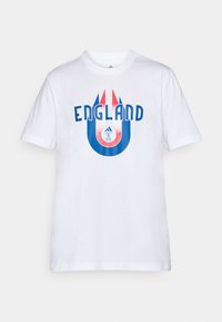 Hvid bomulds t-shirt med "ENGLAND" i fed blå tekst. Designet inkluderer røde og blå accenter med et cirkulært emblem nederst.
