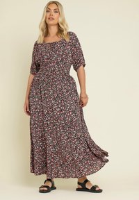 Blommig maxiklänning med svart bakgrund och rosa och vita blommor, korta ärmar, en samlad midja och en fladdrande nederkant.