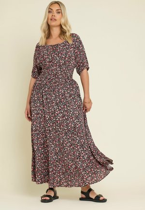 Robe maxi florale avec un fond noir orné de fleurs roses et blanches, des manches courtes, une taille froncée et un ourlet fluide.