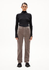 Brown corduroy pants with straight cut and front pockets, paired with a fitted black ribbed turtleneck sweater featuring subtle speckles.