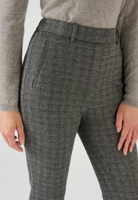 Grijze broek in visgraatpatroon met een mid-rise taille, zijzakken en slim fit, gecombineerd met een gestructureerde grijze trui.