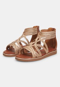 Ruske maateplatåsandaler med gyldne flettede stropper og lukket hæl. Glat læderindlæg og struktureret gummisål. Åben tådesign.