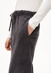 Koolzwarte corduroy broek met een elastische tailleband en trekkoord, voorzien van zijzakken en verticale ribbels.