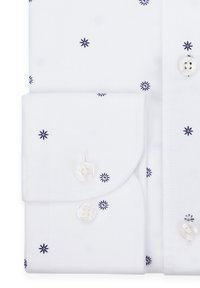 Biała koszula z guzikami, zdobiona granatowymi wzorami w kształcie słonecznego promienia, z mankietem na złożeniu z guzikiem oraz gładką bawełnianą teksturą.
