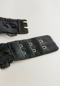 Crna čipkasta i tkaninska naramenica s zlatnim metalnim dijelovima. Ima tri kopče na kuku i očicu te valovitu čipkastu detalj na jednom kraju.