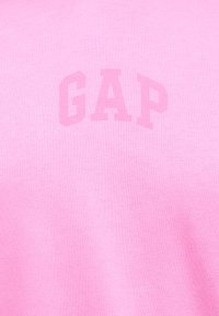 Tissu rose avec le logo GAP en relief et en ton sur ton, centré sur la surface.