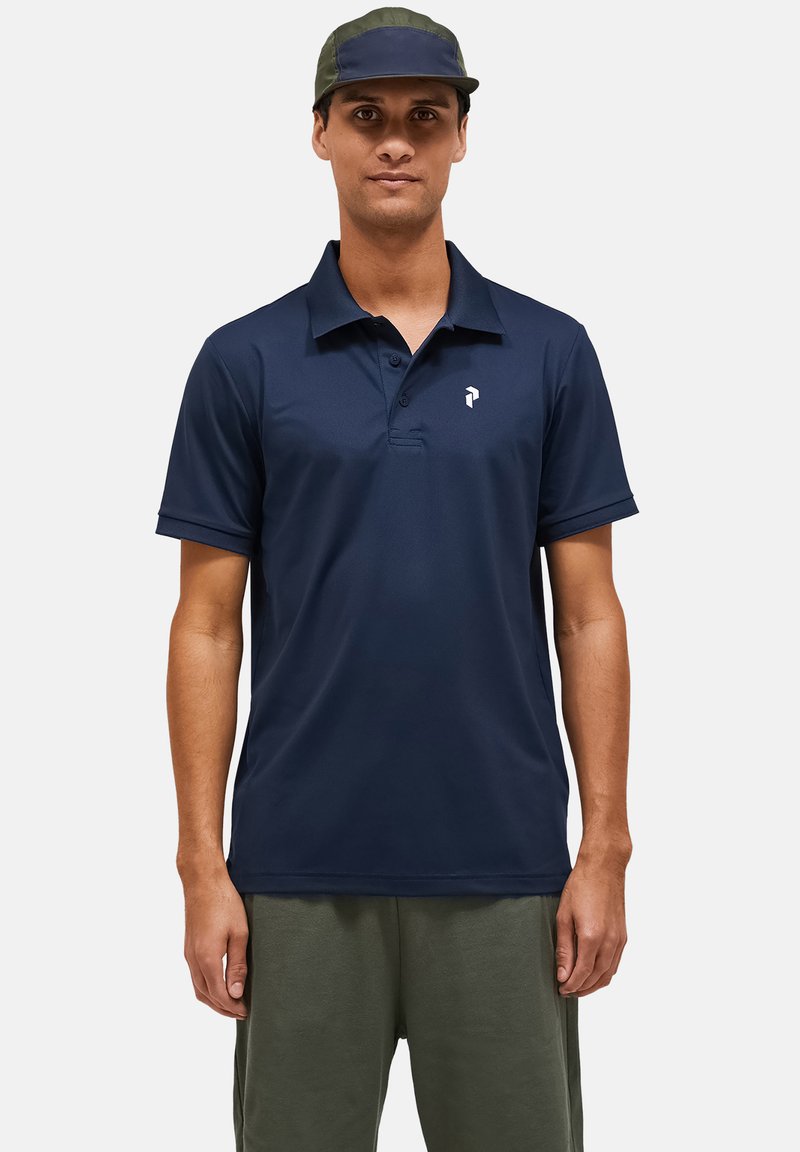 Marineblauw poloshirt zonder patronen, korte mouwen en een knoopsluiting met drie knopen. Bevat een subtiele logo op de linkerkant van de borst.